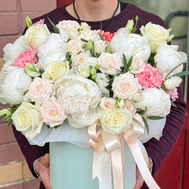 Пионы, розы и эустомы в коробке (в руках флориста)